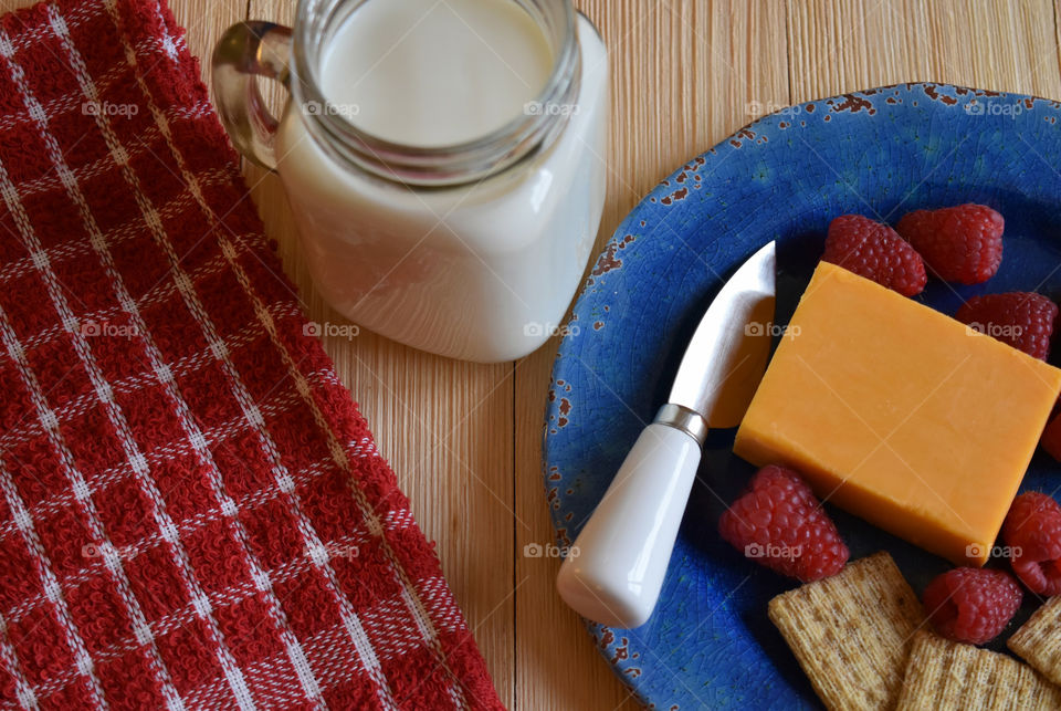 Cold glass of milk with plate of fruit and cheese