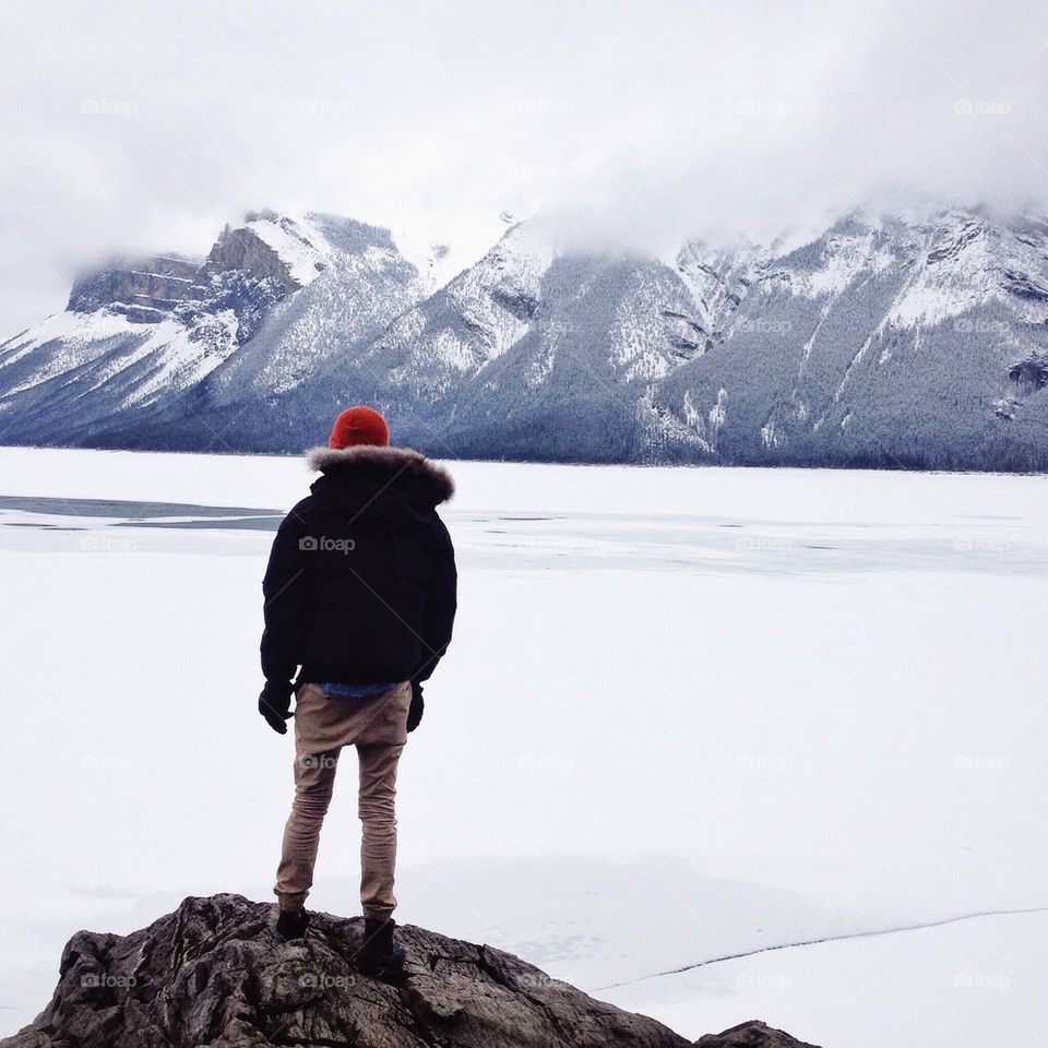 Rear view of man standing on rock at winter