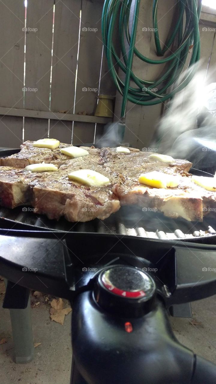 grilling some T-bone steaks on an electric grill on a patio in Citrus Heights California