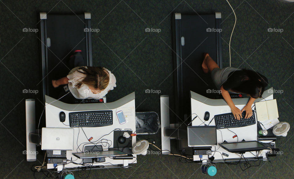 Man and woman standing on treadmill using computer