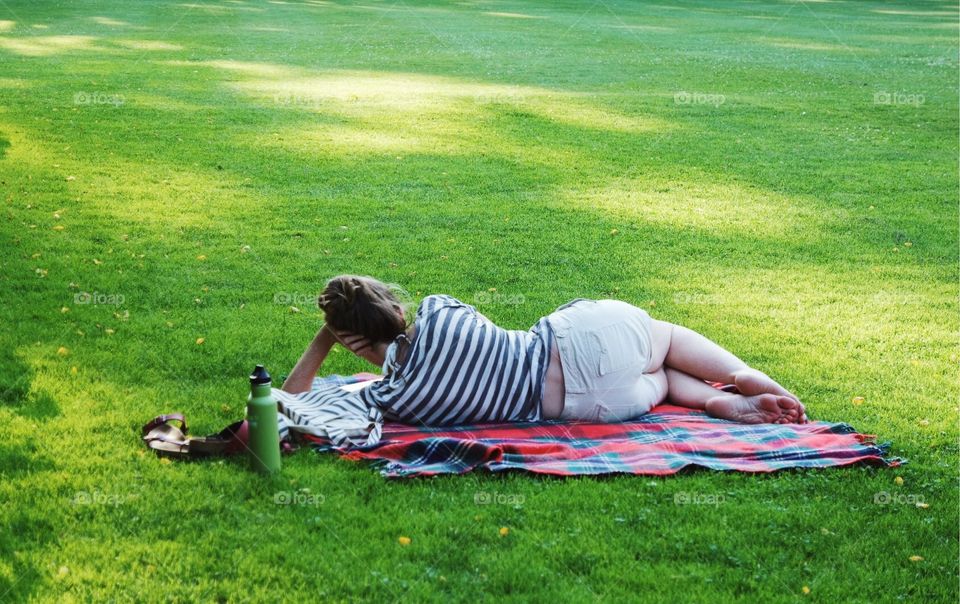 Girl chilling in the park reading in the summer