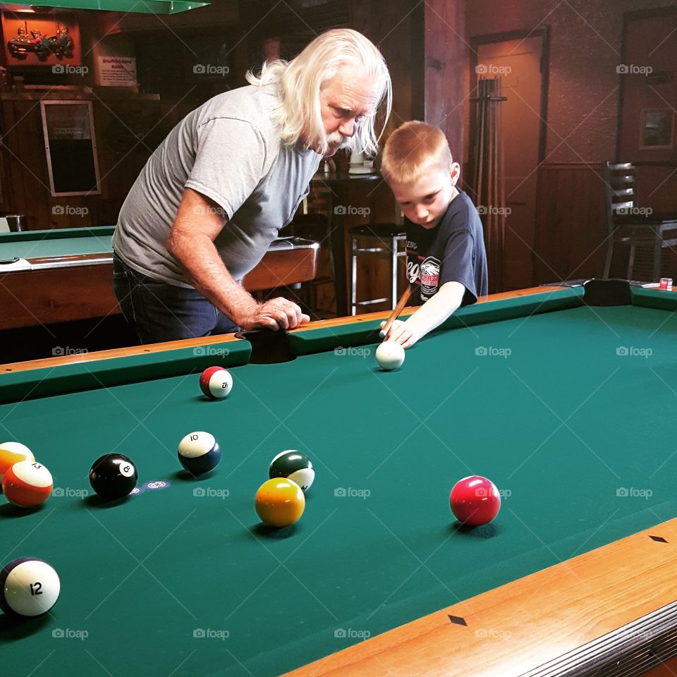 Grandfather teaching his grandson billiards