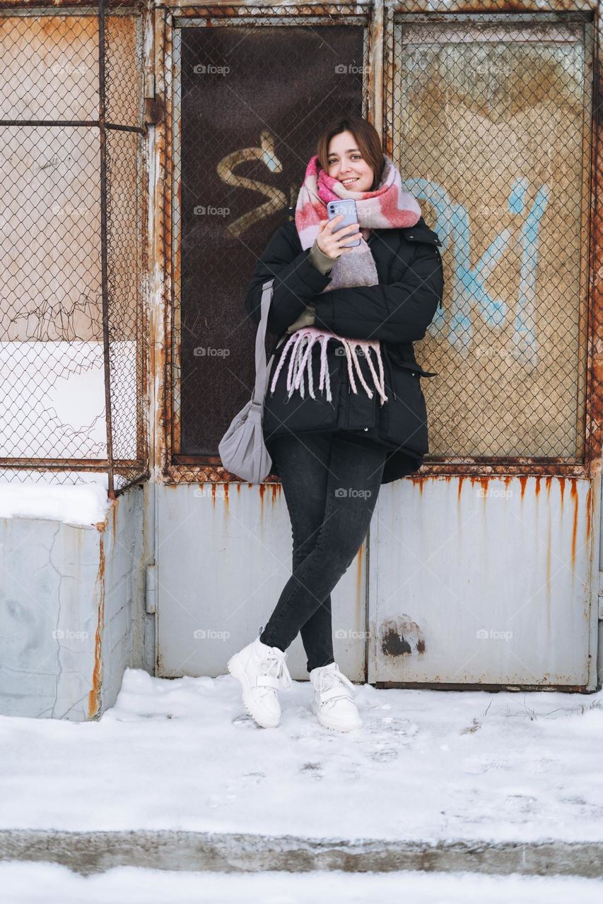 Young woman with mobile phone in white Dr. Martens boots in winter 