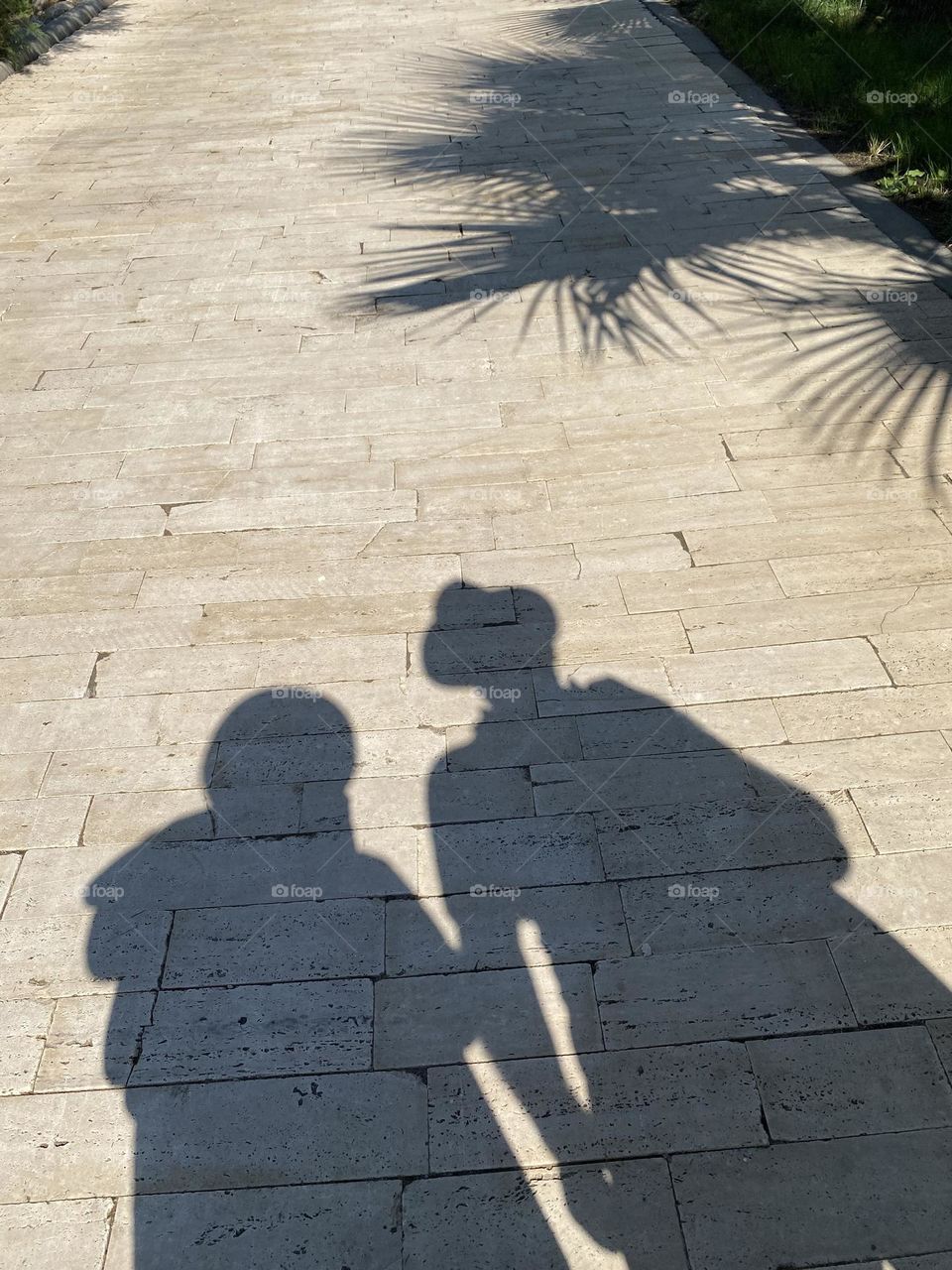 Shadows of man and woman with hats and shadows of palm tree 