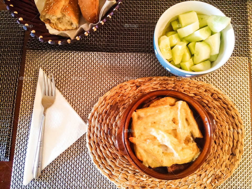 moussaka and bowl with cucumber in pieces, olive oil, salt