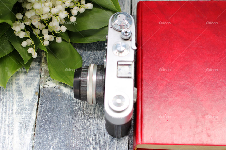 A bouquet of lilies of the valley, a camera and a book