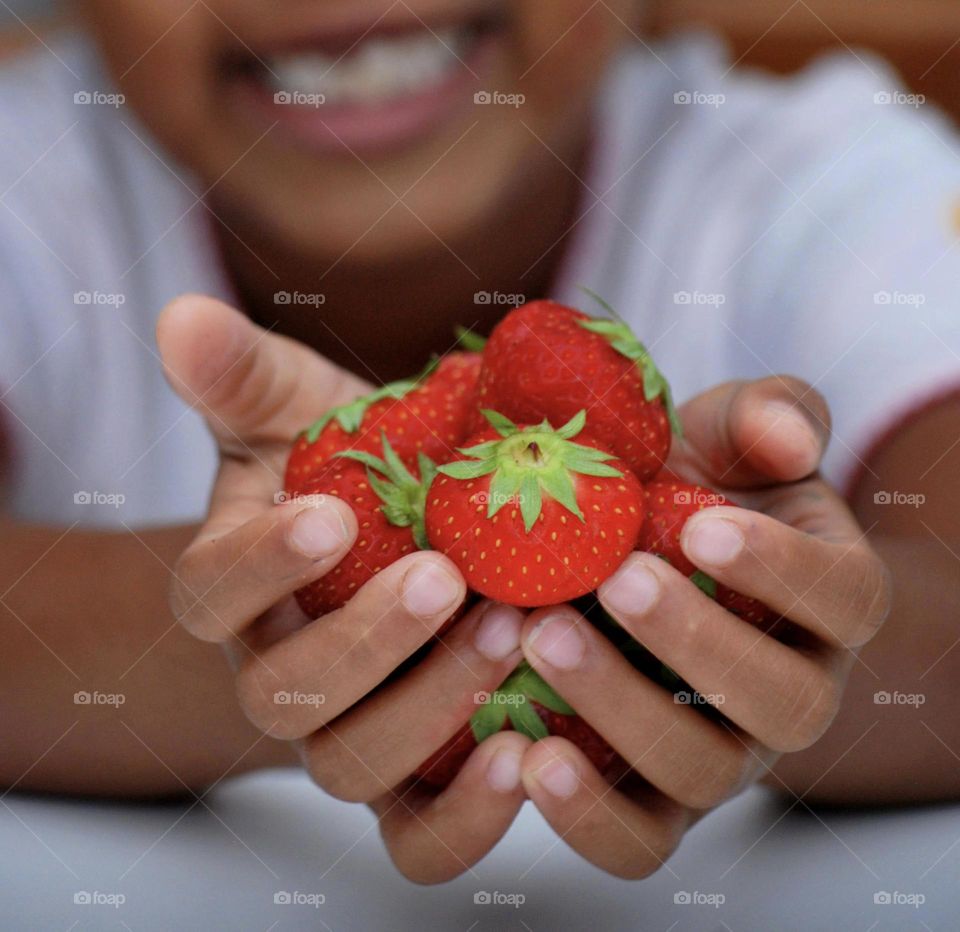 Girl of mixed race holding strawberries in her hand