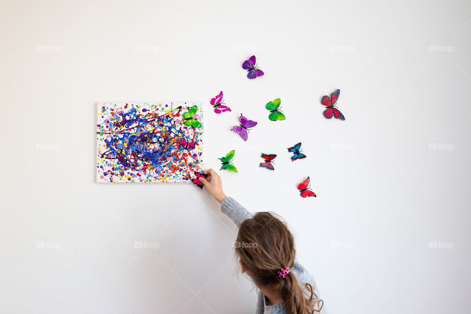 Young artist reinventing Jackson Pollock like painting with butterflies flying out of canvas.