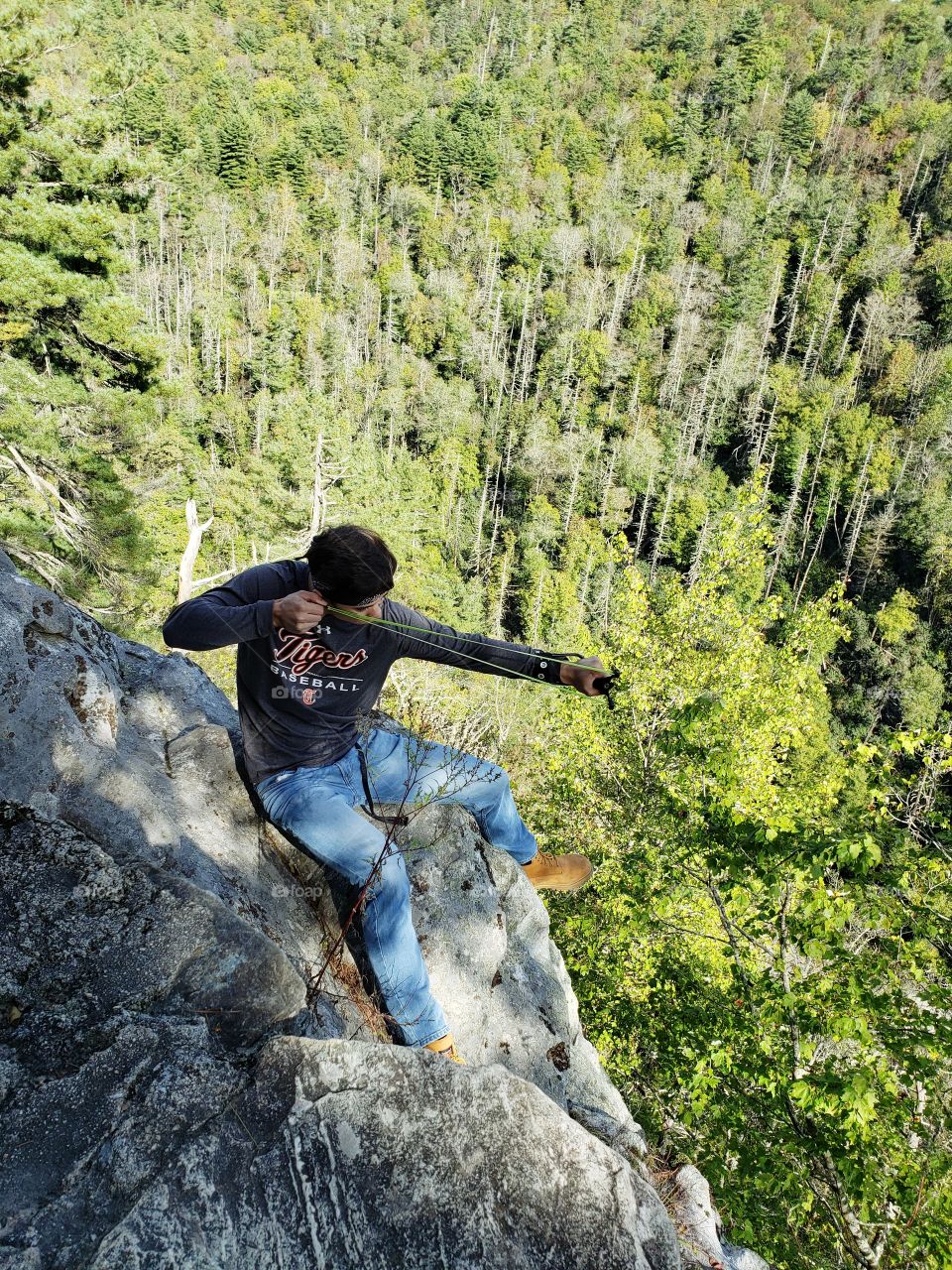Aiming a slingshot while sitting on a cliff