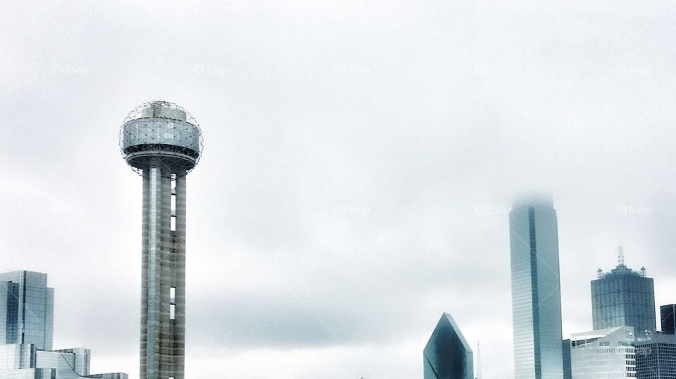 A foggy day in Dallas Texas USA Reunion tower and other buildings in downtown covered by clouds on a blue gray winter's day