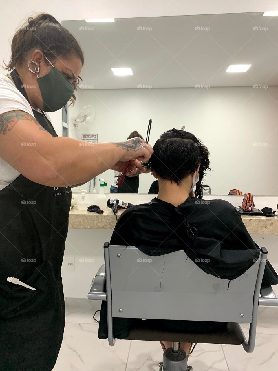 Hairdresser cutting girl's hair