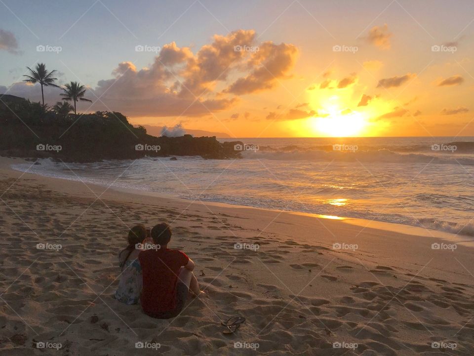 Couple watching a romantic sunset at Shark’s Cove, North Shore, Oahu