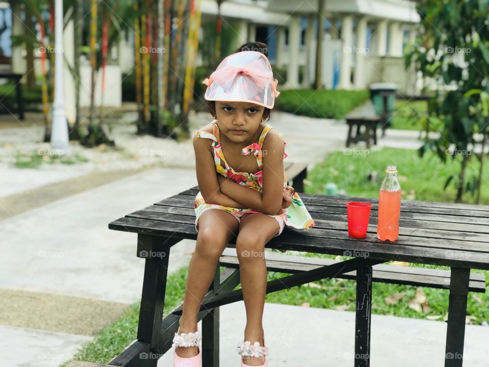 Angry girl sitting on table and looking seriously at something 