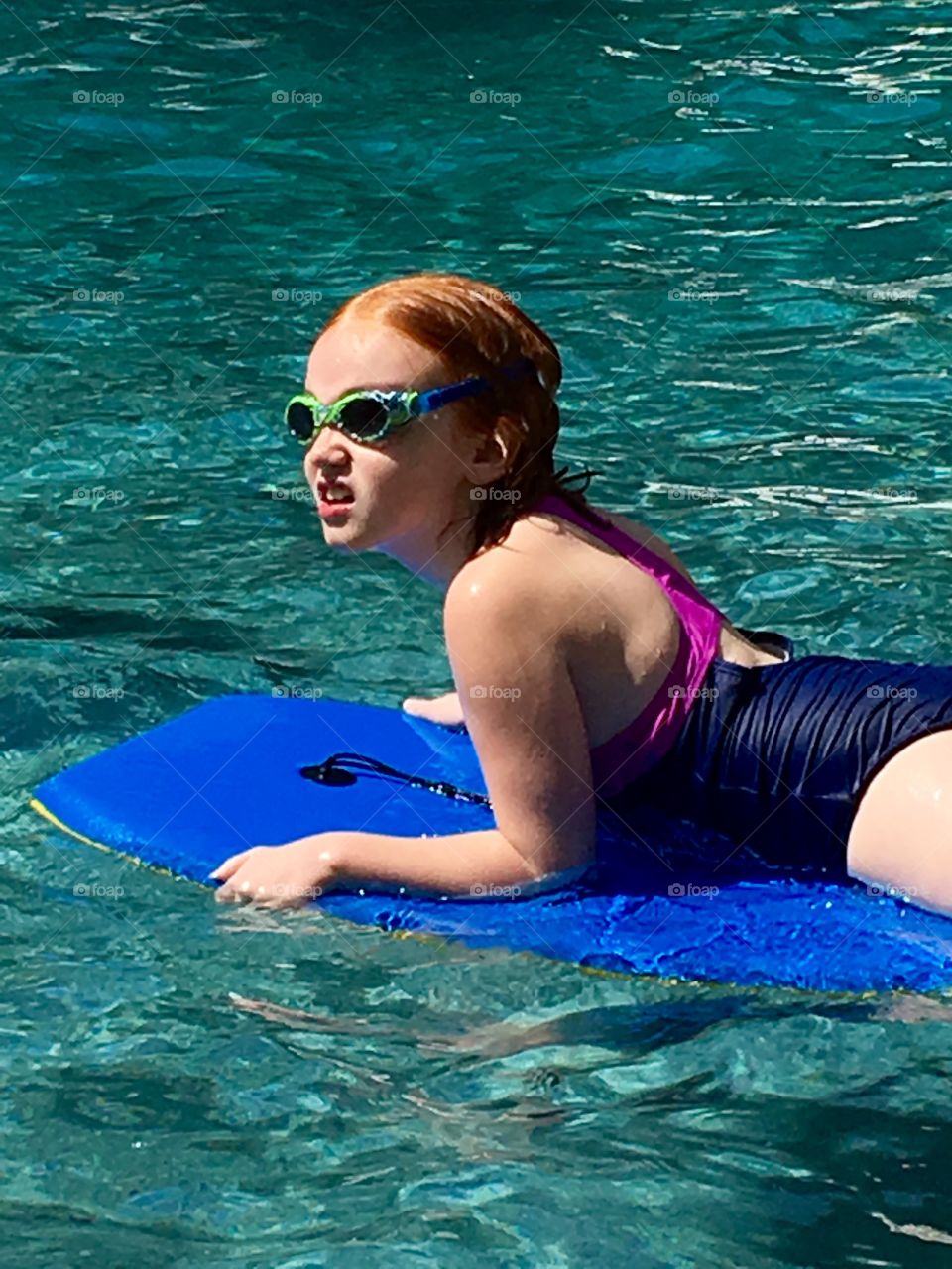Child floating on raft in swimming pool. 