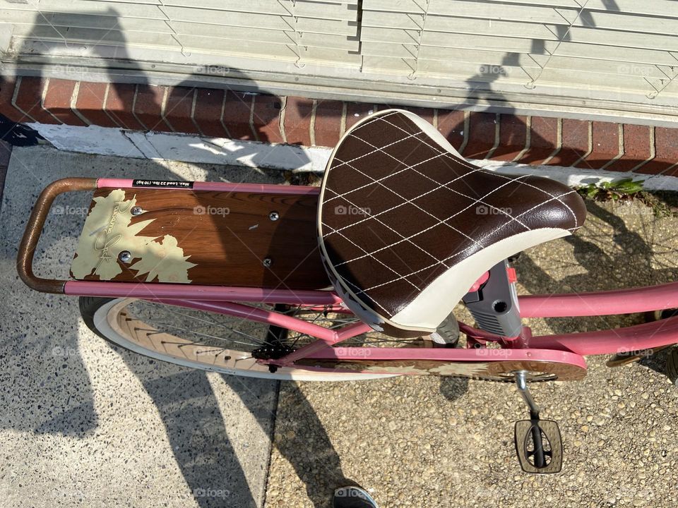 The decorative seat and stand of a pink bike that was parked outside a beauty salon in the town of Point Pleasant Beach, NJ. Such a pretty bike. My shadow and the tip of my sneaker are also in the photo, but I like that. It’s art so let’s have fun!