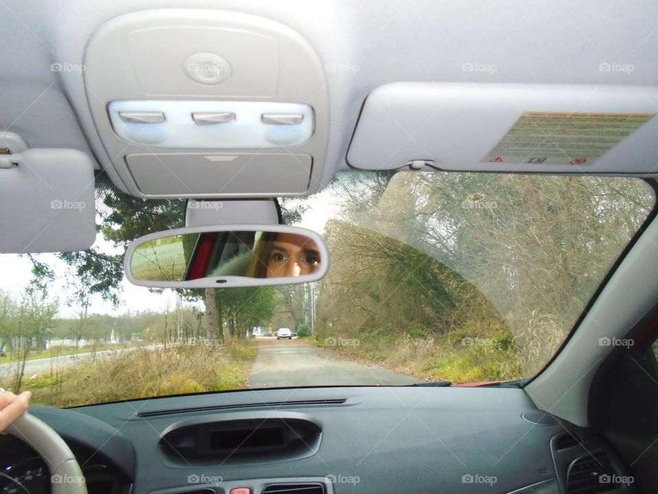 Woman face in the car mirror while driving