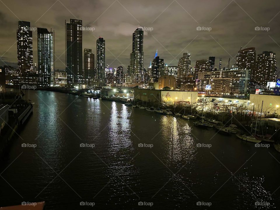 This is “Newtown Creek” at night seen from the “Pulaski Bridge” that connects “Greenpoint”, Bklyn to LIC, Queens presenting a glorious look at NYC, the city they call the “Big Apple”. We see “Brooklyn”, LIC and “Manhattan”. 2023. Hypnotic Productions