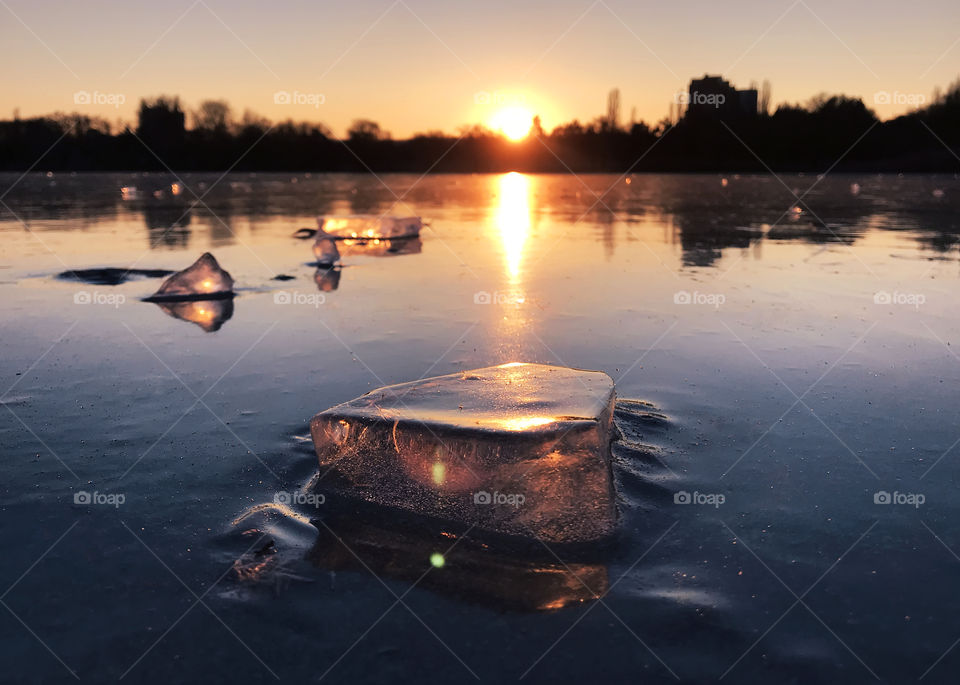 Pieces of ice on frozen lake at sunset 