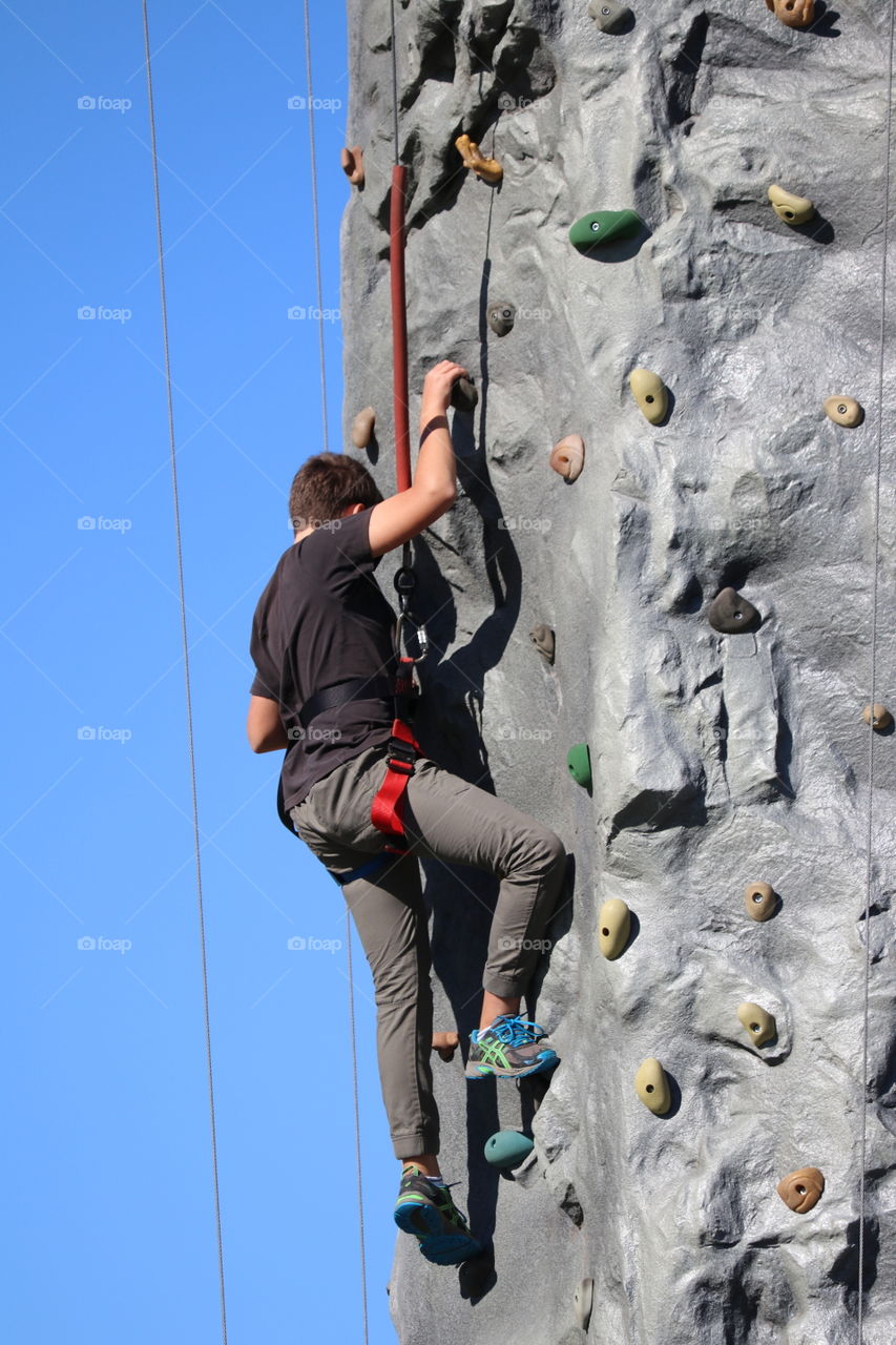 Twelve year old boy rock climbing in outdoor rock climbing facility 