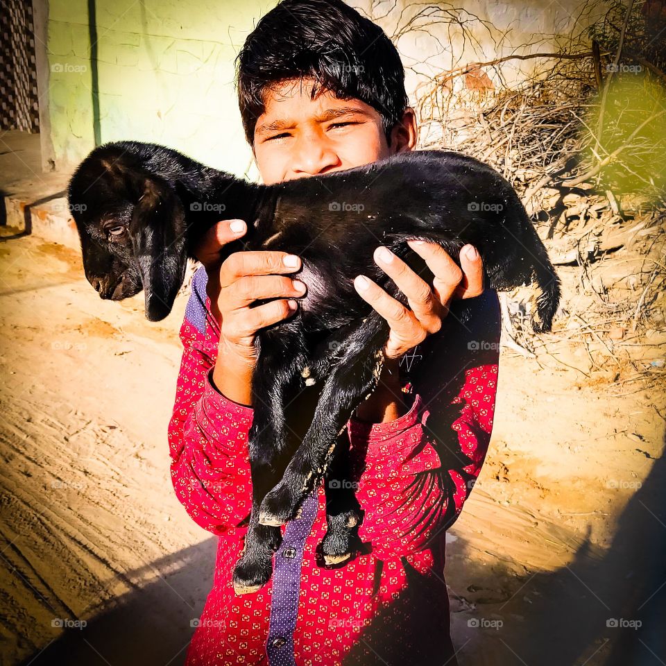 In this photo a boy has kept a 4-day goat baby with love in his hands..