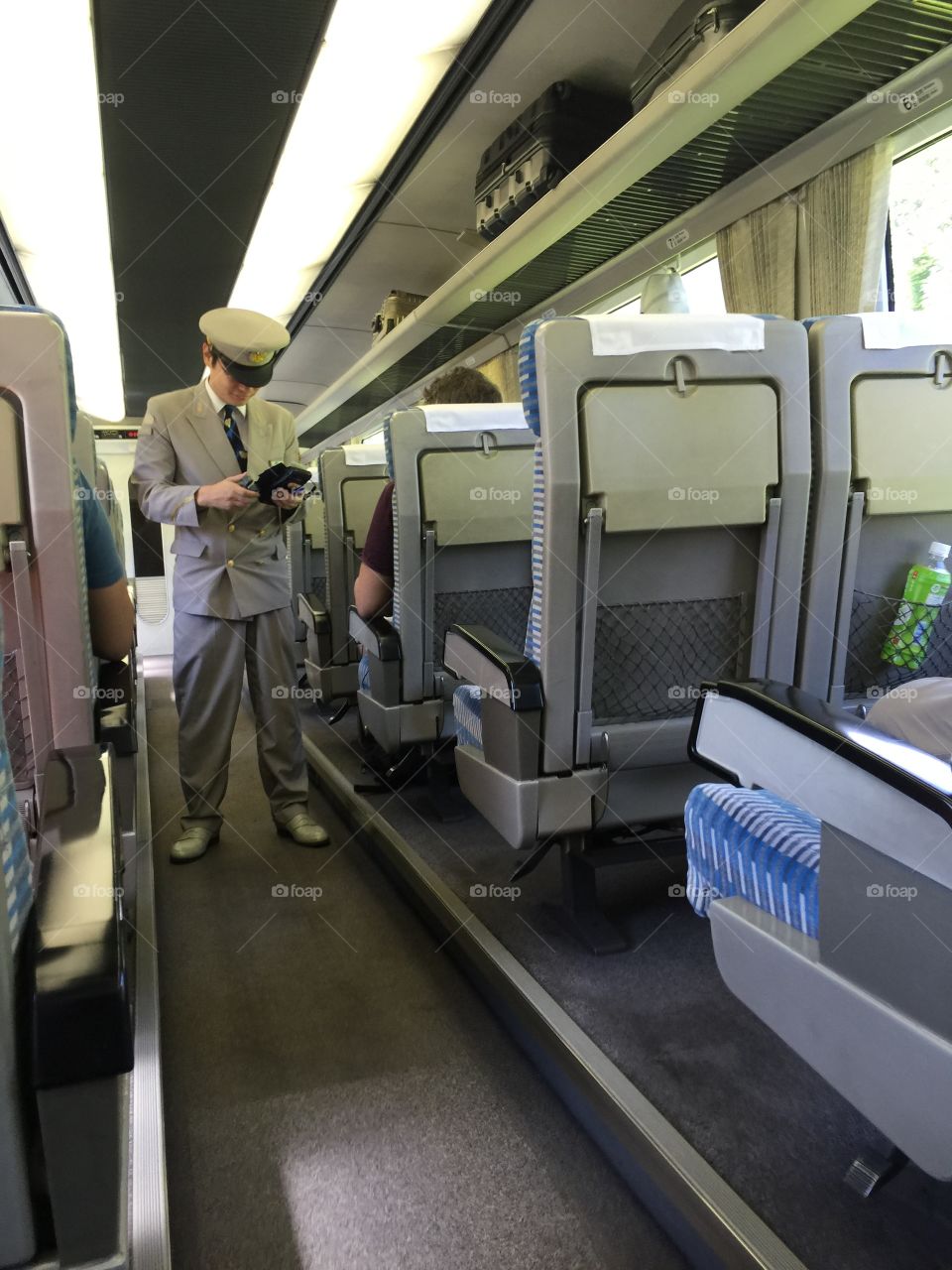 In the high speed Shinkansen train, the conductor walks through the corridor checking tickets from passengers.