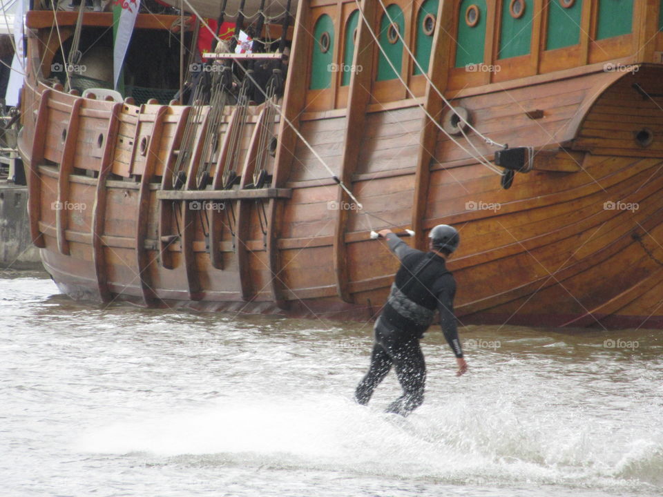 The matthew ship and a man looking very small next to the matthew  on water ski