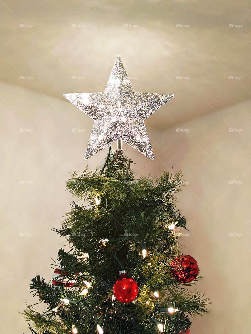 Light up star tree topper on top of a Christmas tree
