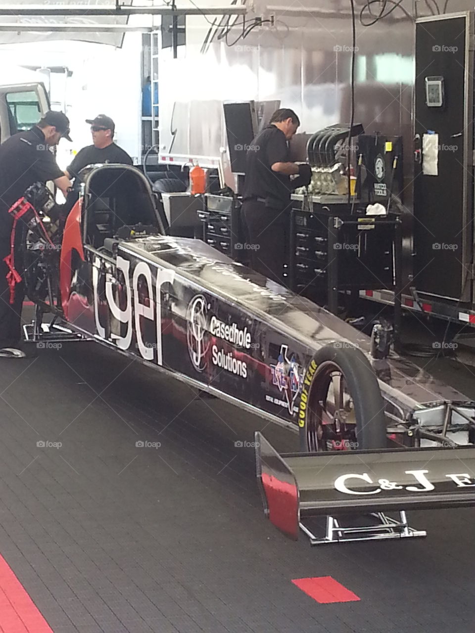 pit crew work on car for next round. day at an NHRA EVENT