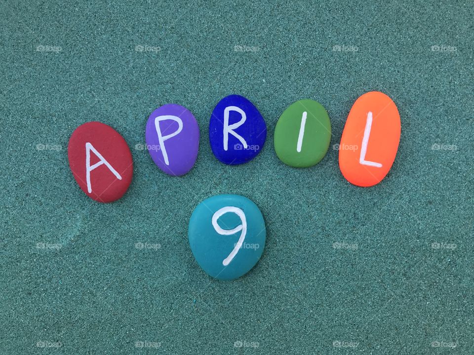 9 April, calendar date on colored stones over green sand 