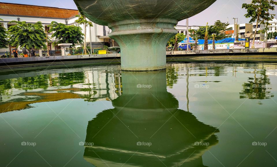 a pond in a city park casts a shadow