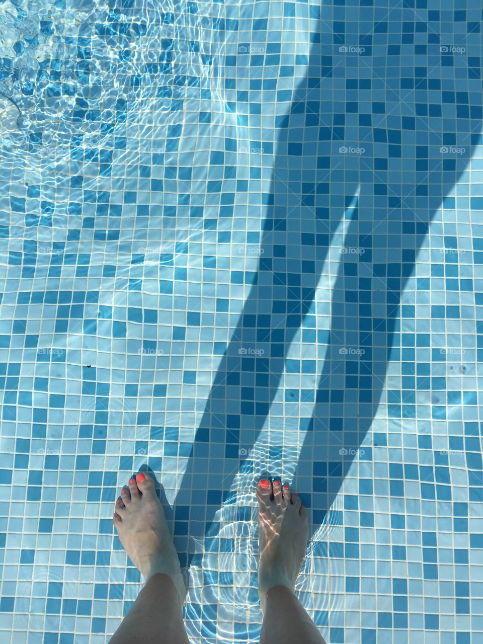 Enjoying a moment of bliss cooling my toes in the water with the sun creating my shadow in the pool. 