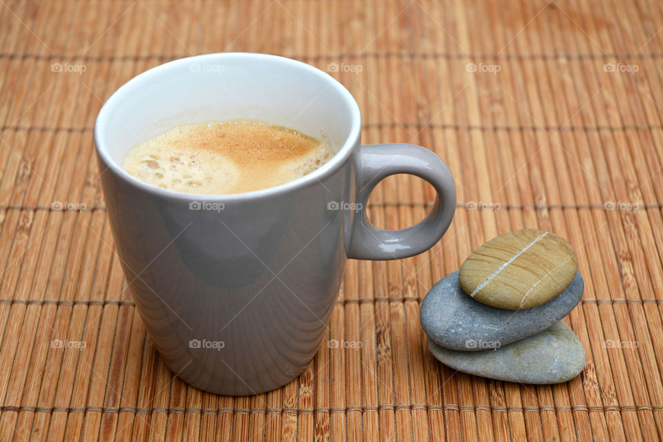 cup of coffee on a bamboo wooden background with zen cairn stones