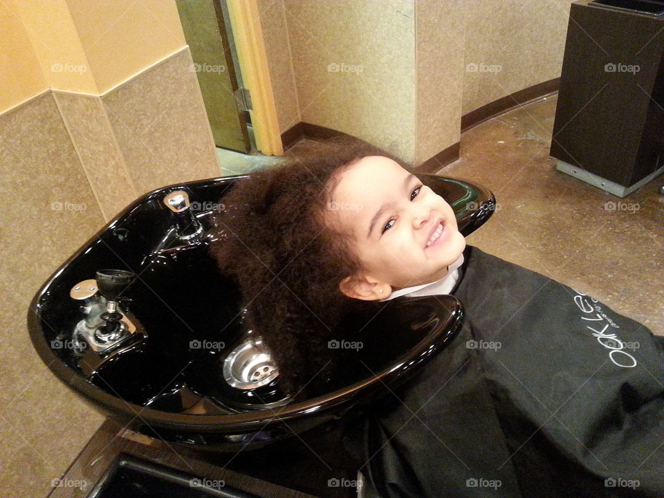 Happy girl head on sink in salon