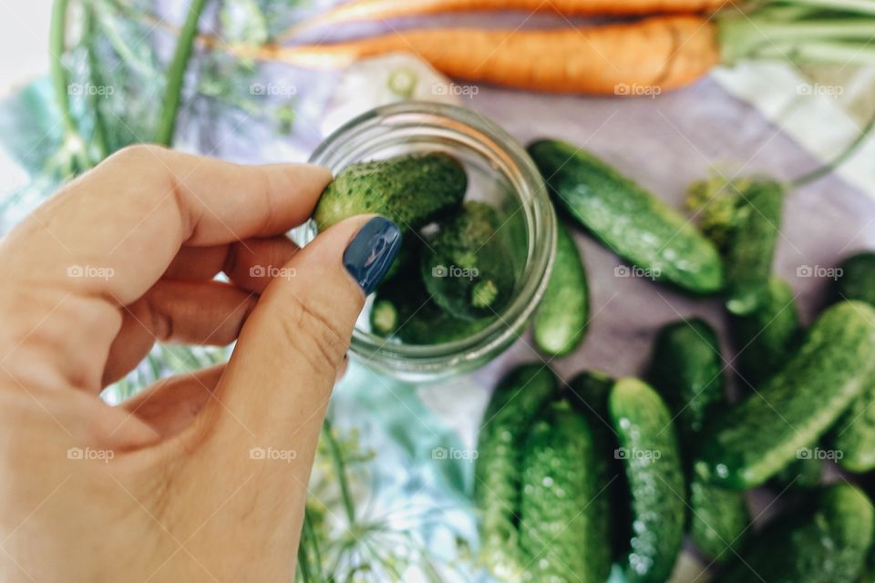 Person removing cucumbers from jar