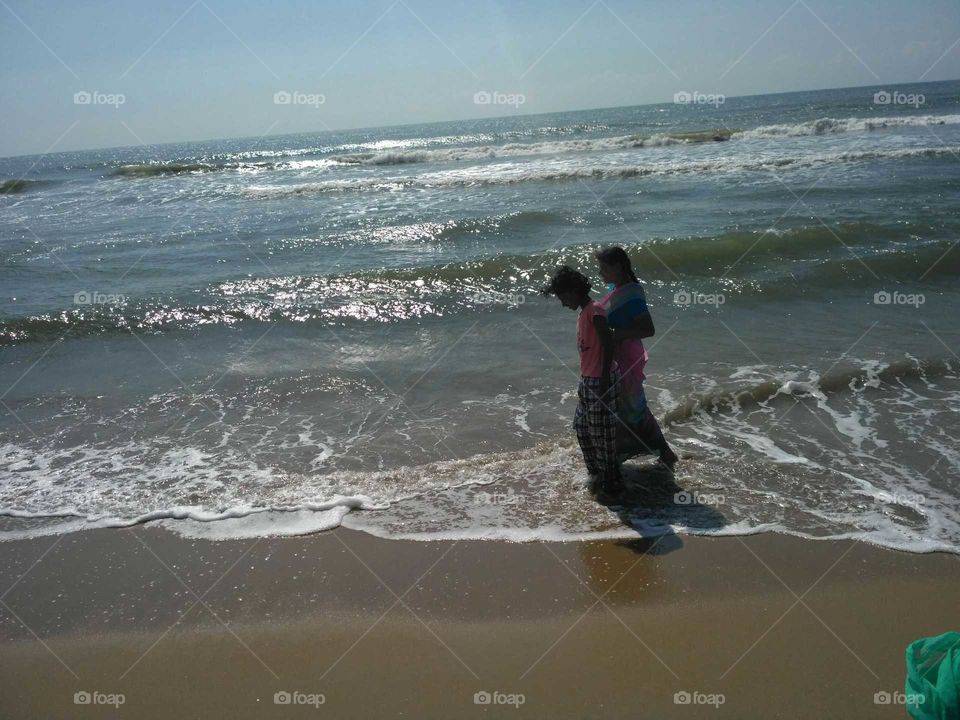 Woman walking with her child on sandy beach