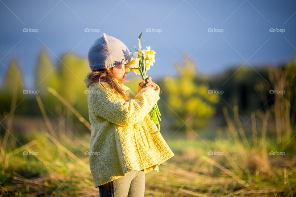 Little girl with narcissus bouquet in spring park