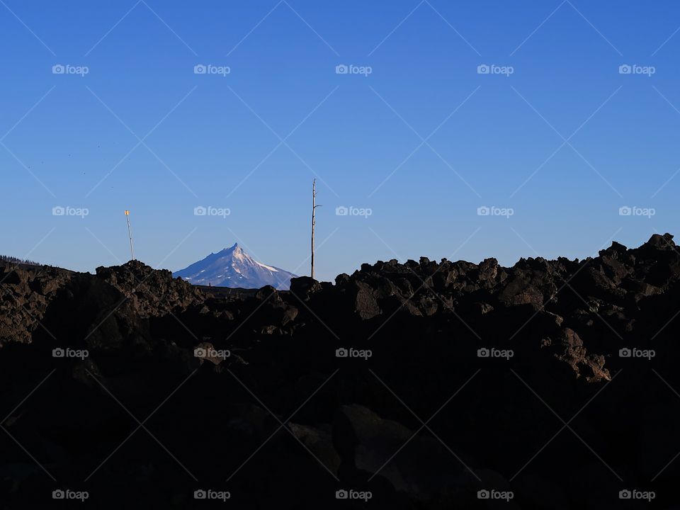 Morning sunrise on Mt. Jefferson in Oregon’s Cascade Mountain Range with a field of lava rock on a fall day with clear blue skies.                      