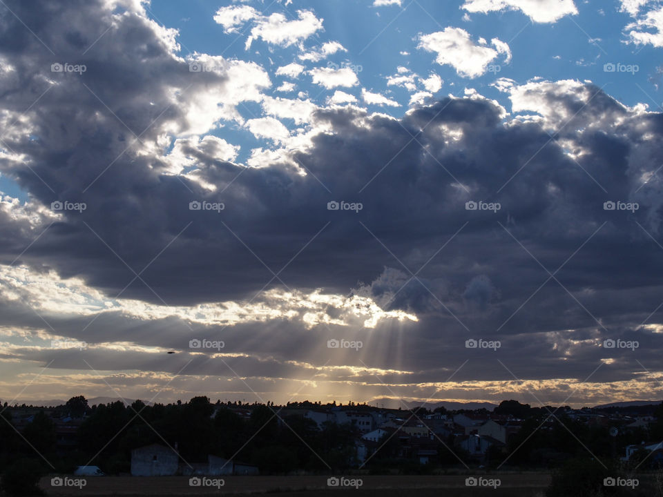 Landscape, sky with clouds and sun rays that illuminate the village