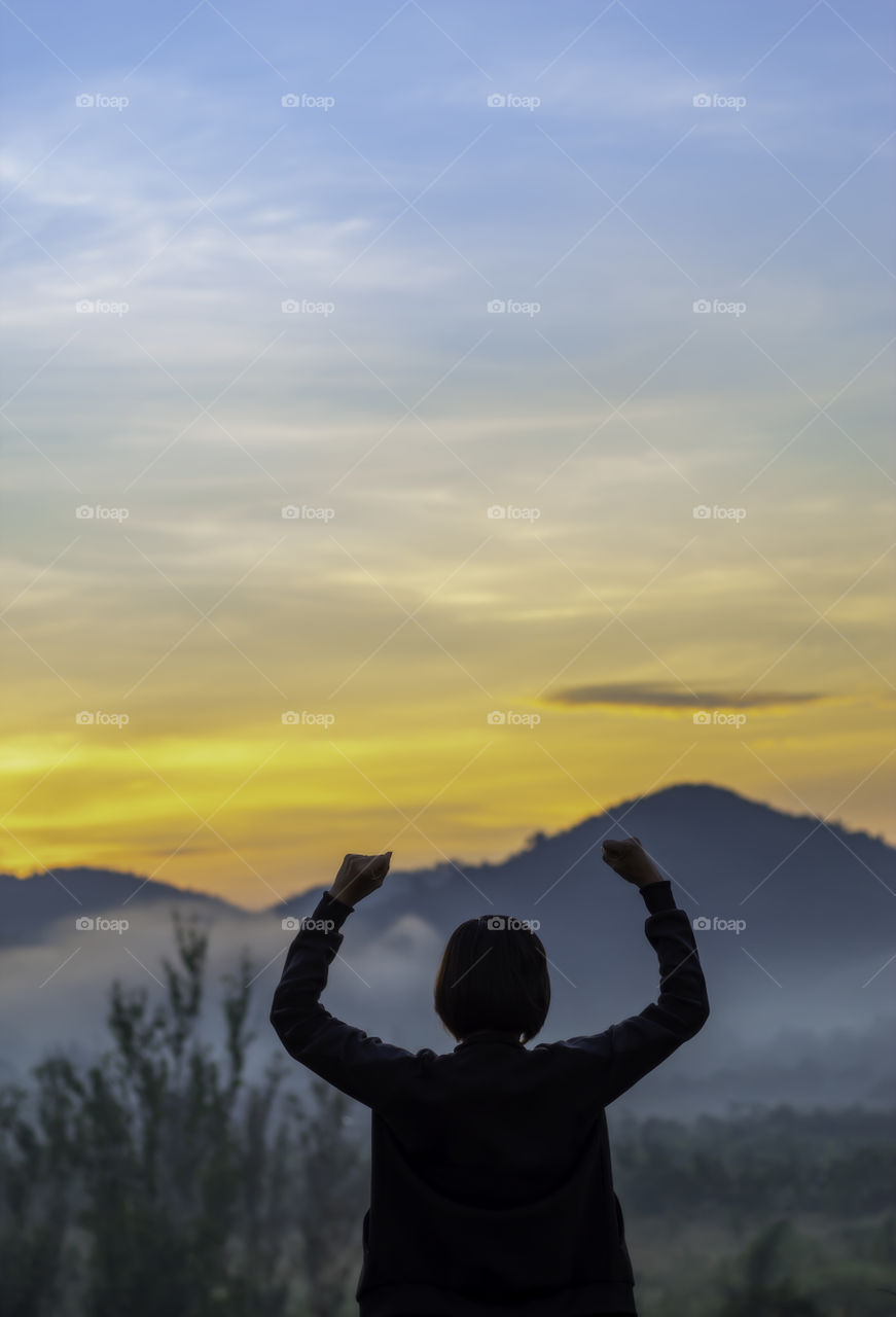 Blurry morning sun light behind the mountains and Women raise their arms.