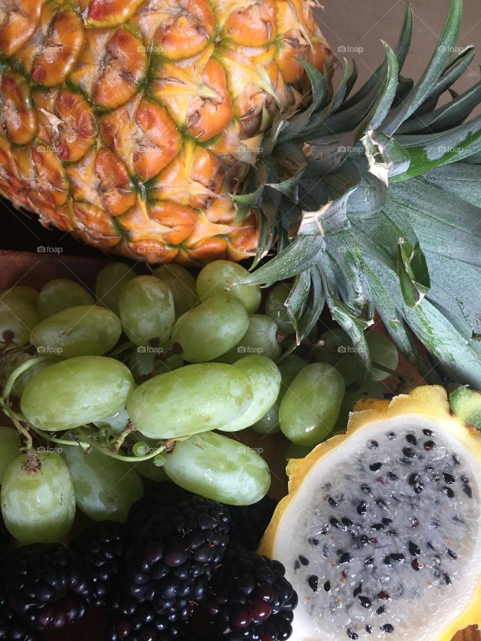 Grapes, pineapple and dragon fruit on a wooden plate