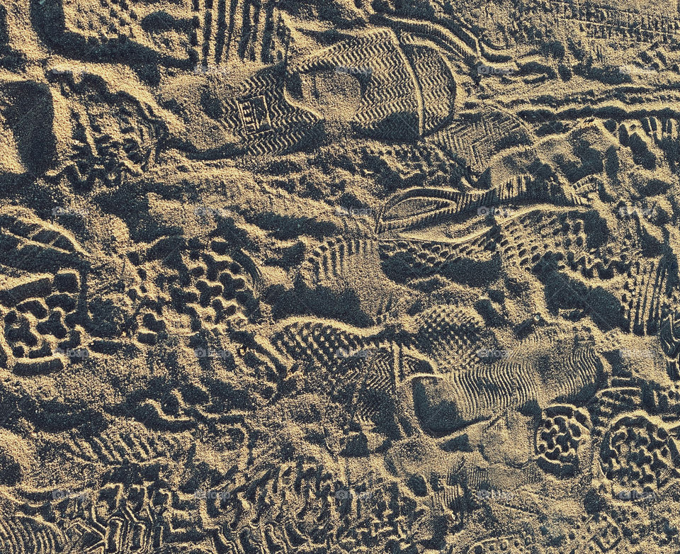 Sneaker and running shoe prints in sand on a jogging path beside a beach