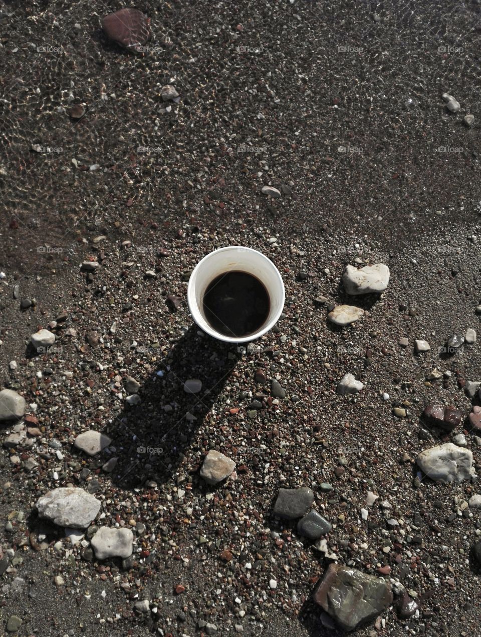 black coffee cup flat lay with dark beach background