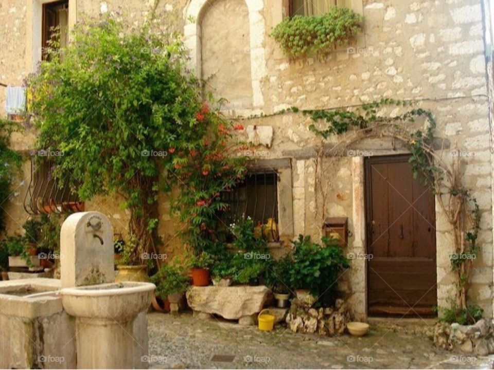 Old street in France. Fountain. Door. Greenery. Stone.