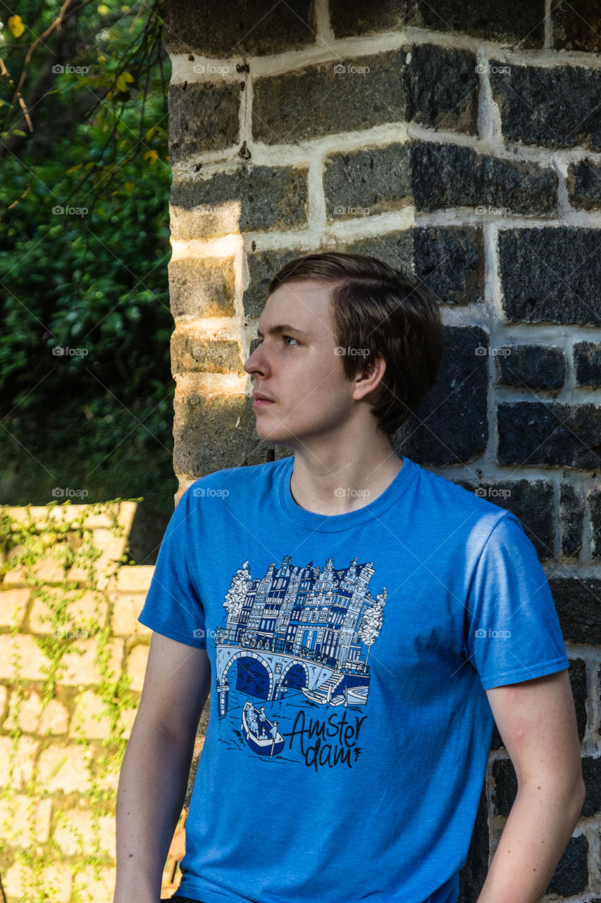 A handsome teenager leaning on the brick wall