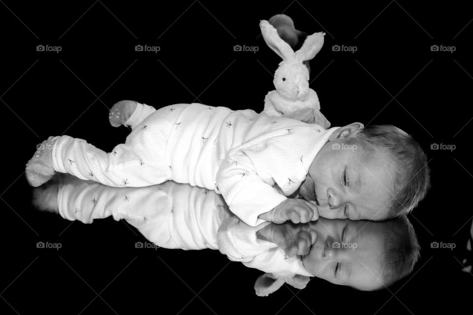 NewBorn baby sleeping at a mirror .
Reflection mirror into the mirror ,makes it cute and light