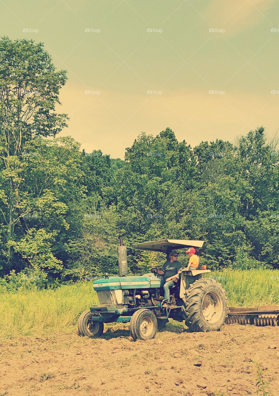 Son father sitting in tractor in field