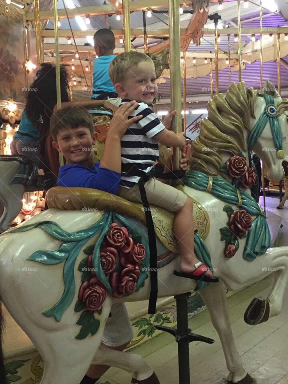 Two boys happily riding the Merry-Go-Round. 