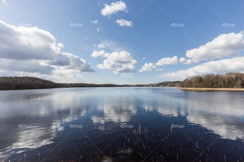 Clouds in the blue sky, reflection on mirror lake water on a sunny day 