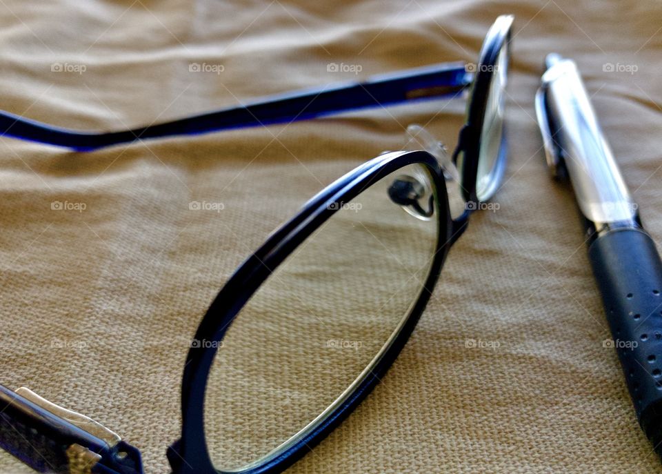 Closeup still life of glasses and pen on fabric