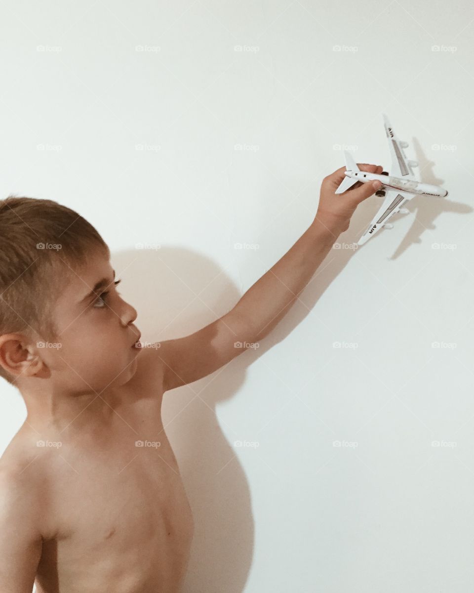 Shirtless boy playing with airplane